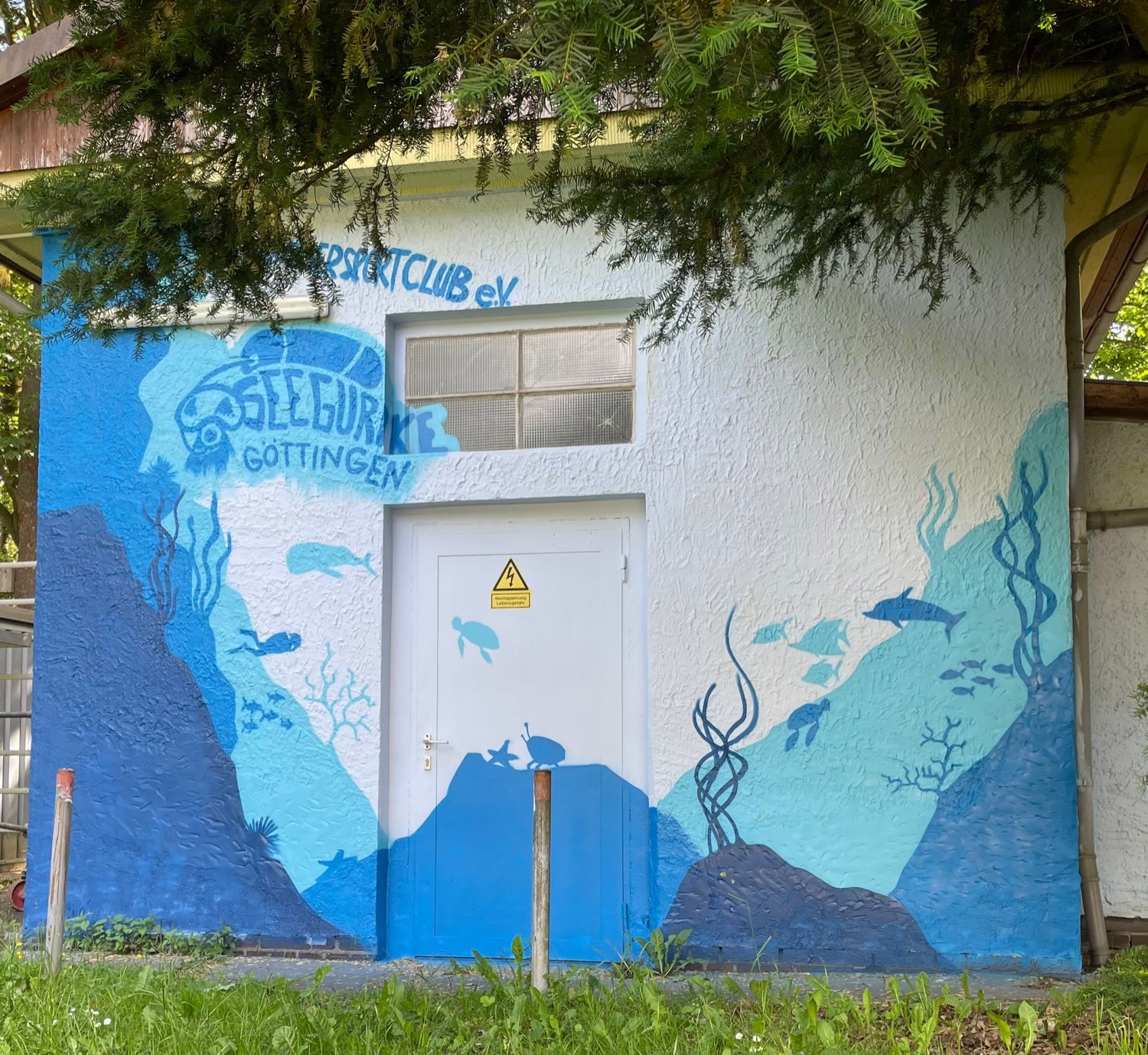 Bemaltes Kompressorhaus mit Seegurke-Schriftzug, Schildkröte und Fischen vor blauem Unterwassermotiv